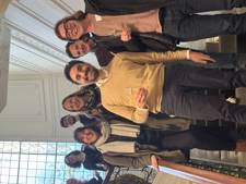 A group of people stands on a staircase, smiling and toasting together with glasses.