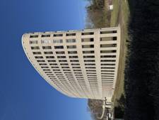 Modern curved office building with large windows against a clear blue sky.