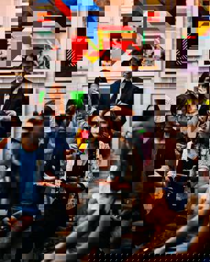 photo of a group of people sitting in a semicircle facing the camera. one of them has the floor.