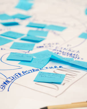 Blauwe post-its en handgeschreven notities op een weekschema met aantekeningen over de infrastructuur.